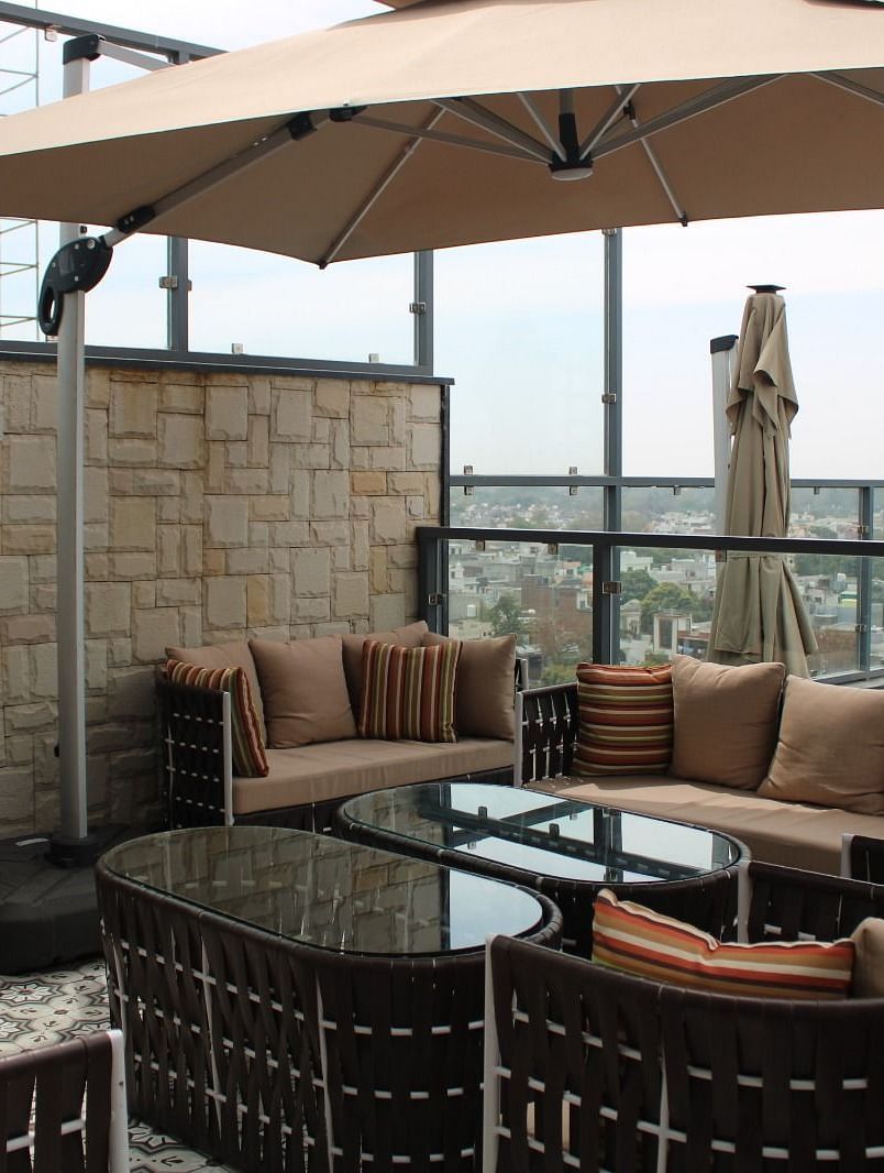 Rooftop lounge featuring sofas, pillows, and a patio offering stunning city views at BluSalzz Residence, Amritsar